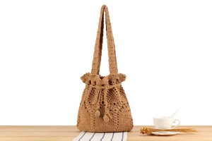 Detail of hand-woven crochet bucket bag with hollow pattern and drawstring closure