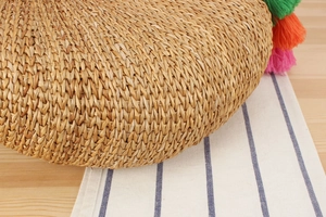 Detailed close-up of handmade straw bag featuring colorful cotton yarn tassels and weave