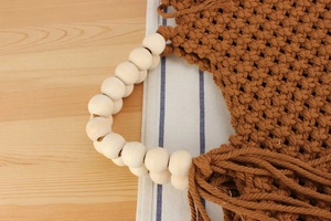 Detail of bohemian cotton rope hand-woven handbag with wood bead handles and long tassels