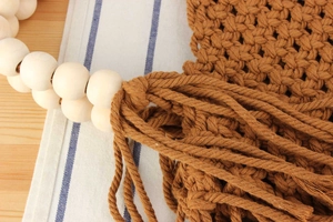 Detail of handmade cotton rope woven bag with wooden beads and bohemian fringe tassels