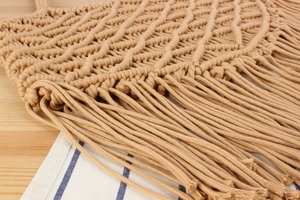 Close-up of bohemian macrame cotton rope bag with intricate weaving and long fringe