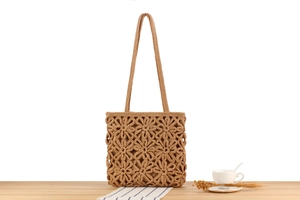 Détail d'un sac cabas en corde de coton bohème avec motifs floraux sur une table en bois