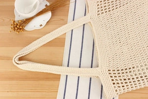 Close-up of cream crochet tote bag showing detailed hollow knit mesh texture on table