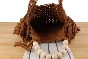 Detail of woven cotton rope handbag with wooden bead handles and side fringe accents