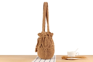 Close-up of khaki woven shoulder bag with intricate hollow crochet and drawstring detail