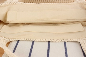 Detail view of the beige straw bag showing the smooth zipper closure and fabric lining