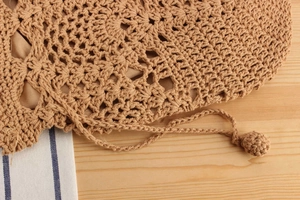 Detail of handmade woven bag with hollow patterns and soft fabric lining on wooden surface