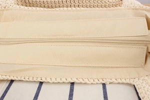 Close-up of beige woven straw bag featuring secure zipper closure and soft inner lining