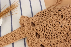 Close-up of handmade crochet weaving pattern and inner lining on a beige straw tote bag