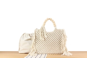 Detail of handmade cotton rope macrame bag with wooden bead handle and fringe accents