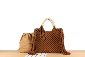 Close-up of handmade macrame tote with wooden bead handles and long fringe tassels