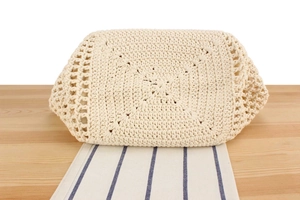 Detailed macro view showing the intricate hand-woven hollow pattern and round base of the beige straw bag