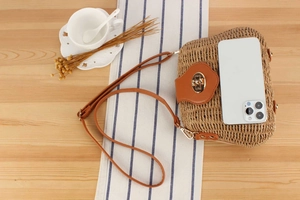 Detail of hand-woven crossbody bag with a gold heart clasp on a wooden table