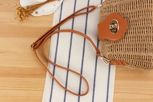 Detail of hand-woven straw crossbody bag with brown leather flap and bear metal buckle