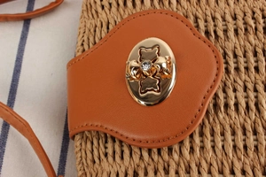 Detailed macro view of straw woven bag with brown leather flap and rhinestone gold lock