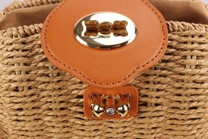 Detail of hand-woven straw bag featuring a brown leather flap and crystal gold twist lock
