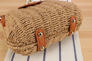 Detail of woven straw bag base with golden metal studs and brown leather reinforcement