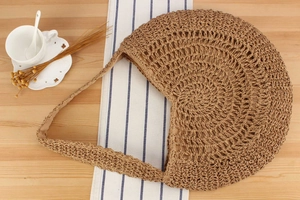 Detail of hand-woven straw shoulder bag with delicate hollow pattern and soft lining