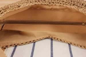 Detailed view of the internal zipper closure and fabric lining of the woven shoulder bag
