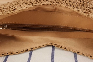 Detail view of woven straw bag with fabric lining and secure metal zipper closure