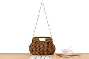 Dettaglio borsa in paglia intrecciata marrone con texture e tracolla a catena oro