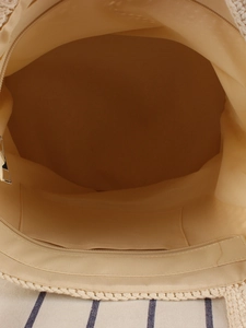 Vertical view of a straw tote bag interior with beige lining and a secure zipper pocket