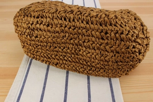 Dettaglio della trama intrecciata e della base ampia della borsa in paglia color caramello