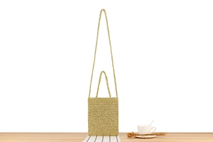 Detail view of a handmade golden crochet bag featuring a woven texture and thin strap