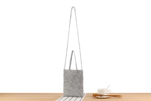 Detail of silver crochet crossbody bag with intricate woven texture and dual handles