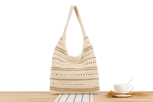 Détail d'un sac cabas au crochet fait main avec rayures crème et marron sur bois