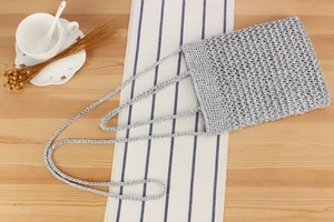 Flat lay of a silver handmade crochet shoulder bag with metallic weave on wooden table