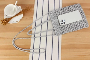 Detail showing a silver crochet mini crossbody bag with a white smartphone inside