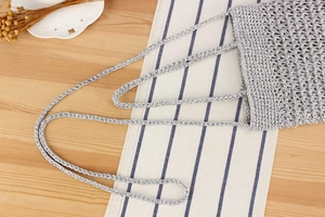 Detailed macro view of silver crochet knit bag texture on a rustic wooden table