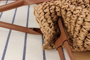 Detailansicht der handgefertigten Strohwebart und des braunen Lederriemens der Strandtasche