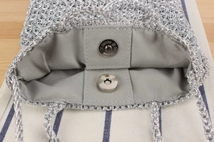 Detailed close-up of silver crochet bag with magnetic clasp and fabric lining inside