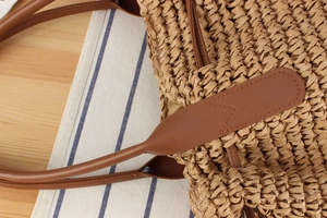 Nahaufnahme des Strohgeflechts und der Nähte des braunen Ledergriffs dieser Tasche