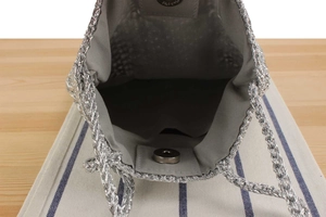 Detail of silver metallic crochet bag featuring magnetic closure and inner lining