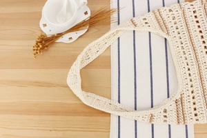 Détail du sac cabas en crochet crème fait main avec rayures brunes sur une table