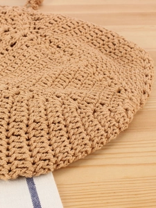 Handwoven khaki straw handbag for beach vacations with intricate crochet pattern details