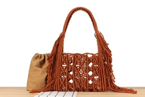 Detail of handmade macramé tote bag with rust orange fringe and canvas drawstring liner