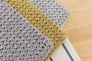 Detailed close-up of handmade crochet bags in metallic gold, silver, and iridescent purple