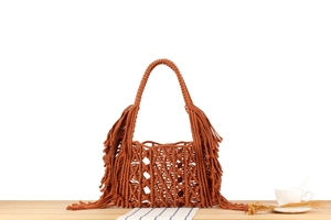 Close-up of caramel hand-woven bag with side tassels and natural fiber textures