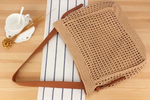 Detail of hollow woven cotton rope tote bag with brown leather shoulder straps