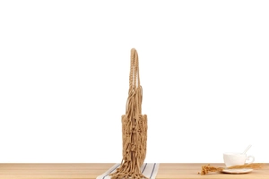 Detail of bohemian hand-woven shoulder bag with long fringes on a rustic table setting