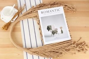Detail view of a handmade macrame tote bag with fringe tassels on a wooden table