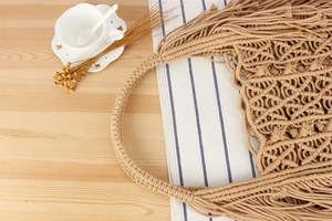 Detailed macro view of handmade macrame woven handbag with geometric patterns and fringe