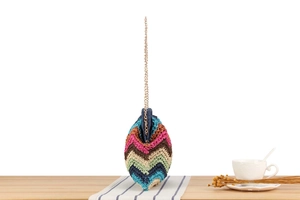 Macro shot of colorful wave pattern woven bag with a sleek gold metal chain strap
