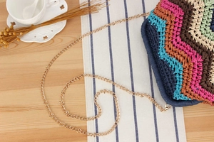 Detailed view of wave pattern handmade crochet crossbody bag with light gold chain strap