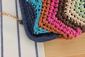 Detailed macro view of multi-color rainbow straw woven bag with gold metal chain strap