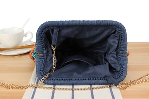 Detailed interior of dark blue woven bag with metal frame and gold chain strap
